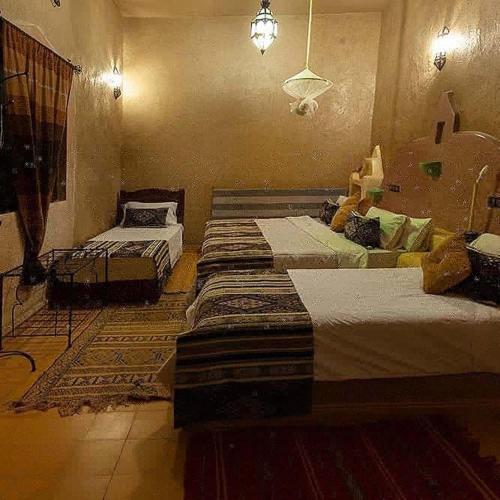 a bedroom with two beds and a rug at Riad Dar Ouzine in Merzouga