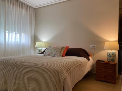 ein Schlafzimmer mit einem Bett, zwei Lampen und einem Fenster in der Unterkunft Piso Ramallosa Nigrán in Nigrán