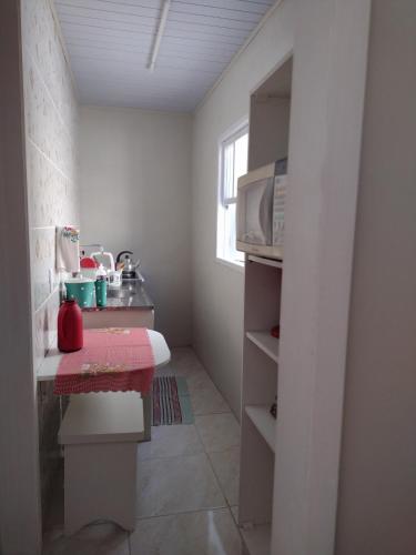 eine kleine Küche mit einem Tisch und einer Mikrowelle in der Unterkunft Kitnet Namorados in Gramado