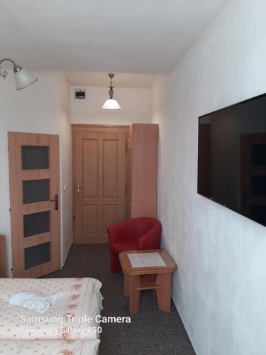 a room with a bed and a red chair and a television at Hotel Vagónka in Studénka