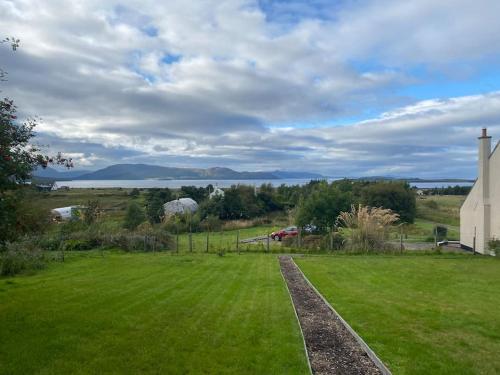 a grassy field with a church and a field with a house at Modern cabin with stunning views & private hot tub in Breakish