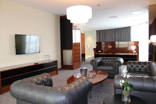 a living room with leather furniture and a piano at Admiral Hotel in Zagreb