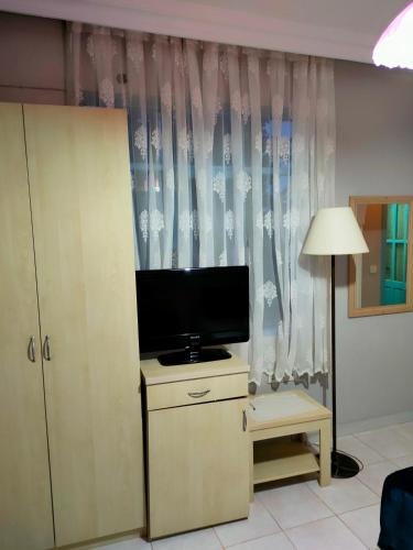 a living room with a tv and a desk with a lamp at Side Erenler Hotel in Side