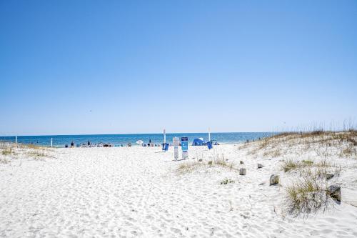 a beach with people sitting on the sand and the ocean at A Wave From It All - Unit B in Gulf Shores