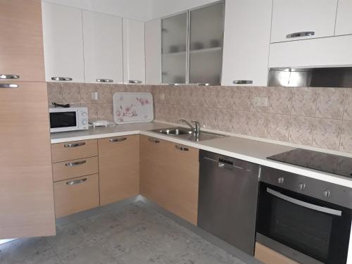 a kitchen with white cabinets and a sink and a dishwasher at Marys Home Apartment Međugorje in Međugorje