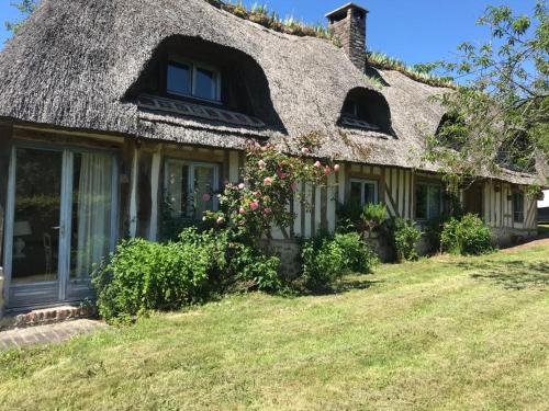 une maison ancienne avec un toit de chaume et des fleurs dans l'établissement Chaumière aux portes d'Honfleur, à Manneville-la-Raoult