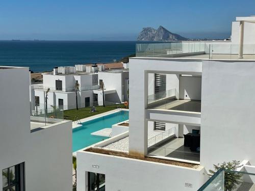 a white building with a swimming pool and the ocean at Links II 505 Duplex 2bedroom Apartment GOLF Alcaidesa SPAIN in Alcaidesa