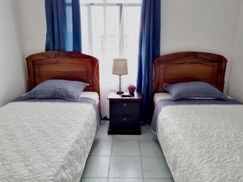 2 Betten in einem Schlafzimmer mit blauen Vorhängen und einem Fenster in der Unterkunft Entire Homy apartment for you, 5 min SJO Airport in Alajuela