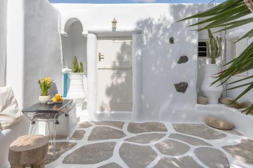 a room with white walls and a floor with a table at Cassaris Mykonos in Drafaki