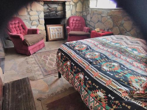 a bedroom with a bed and two chairs and a fireplace at La loma del chivo Llc Stone Cottage alternative building in Marathon