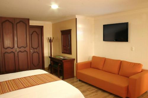 a bedroom with a bed and a couch and a television at Hotel Luxor Pereira in Pereira