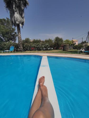 a person laying on the edge of a swimming pool at SERENGETI NAP comfy rooms in Sidari