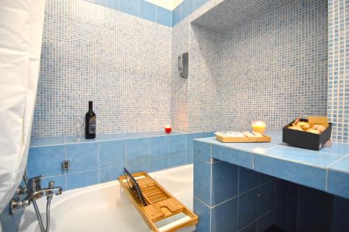 ナポリにあるNapoli Cityscapeの青いタイル張りのバスルーム(バスタブ付)、ワイン1本