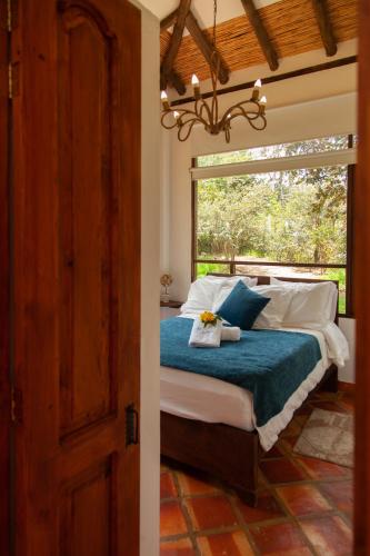 a bedroom with a bed with a large window at Clavellino House en Villa de Leyva - Tranquilidad y Naturaleza en Reserva Natural Urbana! in Villa de Leyva