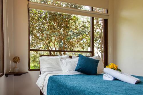 a bedroom with a bed with a large window at Clavellino House en Villa de Leyva - Tranquilidad y Naturaleza en Reserva Natural Urbana! in Villa de Leyva