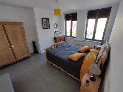 a bedroom with a bed and two windows at Gîte Au Cœur de Cassel in Cassel