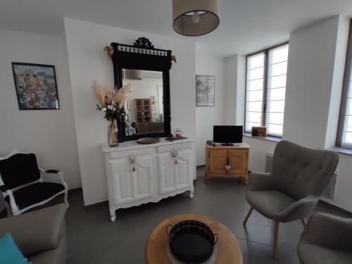 a living room with a mirror and chairs and a table at Gîte Au Cœur de Cassel in Cassel