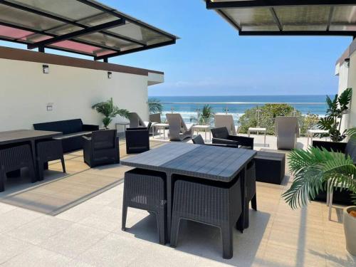a patio with tables and chairs and the beach at Bejuco Beachfront Condo FRENTE A LA PLAYA hermoso condominio NUEVO in Esterillos Este