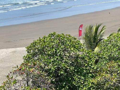 a beach with a red kite sitting on the sand at Bejuco Beachfront Condo FRENTE A LA PLAYA hermoso condominio NUEVO in Esterillos Este