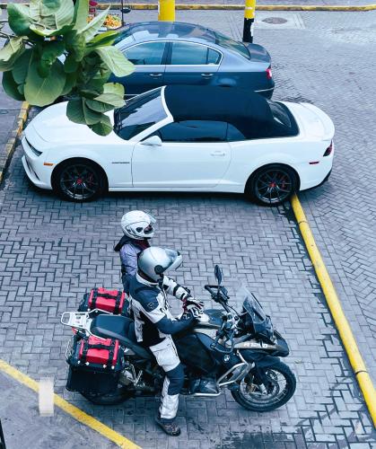 a person sitting on a motorcycle next to a white car at Hotel Plaza San Antonio Arequipa in Arequipa