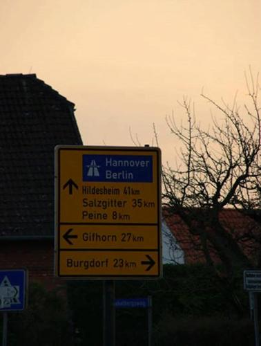 a yellow sign with arrows on a street at Edemissener Gästezimmer in Peine