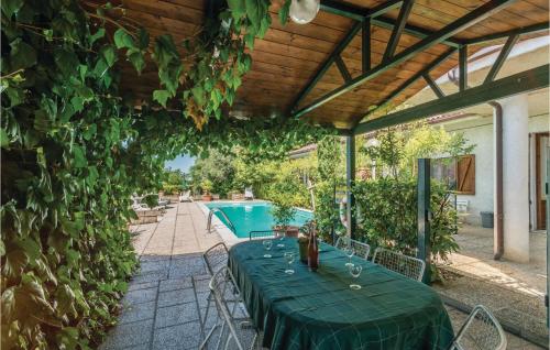 a table with a green table cloth sits under a pergola with a pool at Paucca 2 in San Valentino di Villa