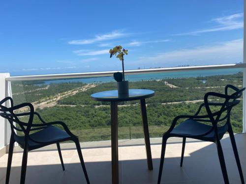 2 sillas y una mesa con un jarrón con flores en el balcón en Condominio Cancún malecón, en Cancún