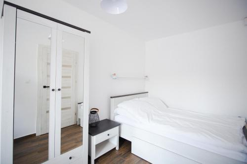 a bedroom with a white bed and a mirror at Lazurowa Fala-2021, Baltic Park in Stegna