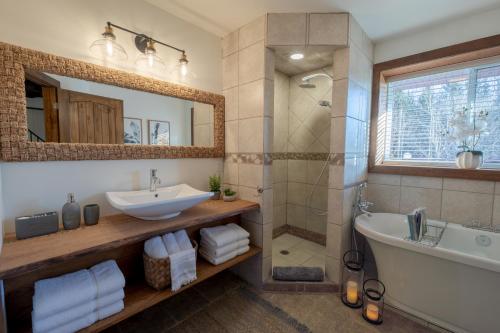 y baño con bañera, lavamanos y ducha. en Breathtaking log house with HotTub - Summer paradise in Tremblant, en Saint-Faustin