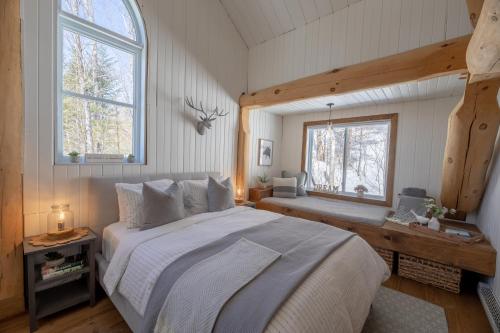 sypialnia z dużym łóżkiem i 2 oknami w obiekcie Breathtaking log house with HotTub - Summer paradise in Tremblant w mieście Saint-Faustin