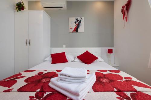 a bed with red and white sheets and red pillows at Palace Central Square in Trogir