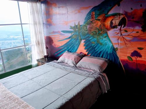 1 dormitorio con un mural de pavo real en la pared en Cabaña del Colibri, la Guacamaya y la Mariposa en Sopo
