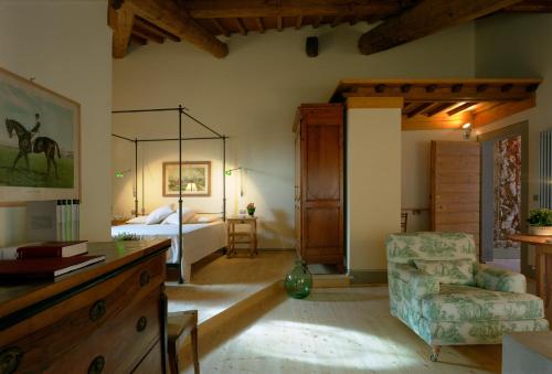 a room with a bedroom with a bed and a chair at Fattoria Casamora - Suites in Pian di Scò