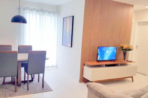 a living room with a table with a laptop on a cabinet at Apartamento CONFORTO CLIMATIZADO prox do SHOPPING NAÇÕES prox ABBA Church - cozinha completa - Ar condicionado - WiFi - Smart Tv 32' - Youtube e Apps - estacionamento privado - Portaria 24h - Acomoda até 8 pessoas - Anfitriã SuperHost no BNB 5 Estrelas in Criciúma