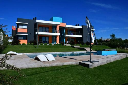 a building with a swimming pool in front of it at Complejo Cuatro Colores - Apart Hotel in Potrero de Garay