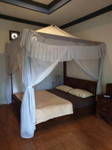 a bedroom with a bed with a canopy at Five Time Homestay in Gili Islands