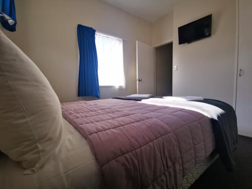 a bedroom with a bed and a window at Airport Birches Motel in Christchurch