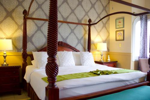 a bedroom with a canopy bed with white sheets at Hotel Victoriano in San Juan del Sur