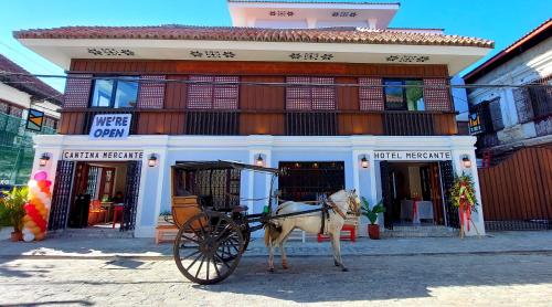 a horse pulling a carriage in front of a building at Hotel Mercante in Vigan
