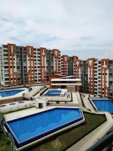 a group of swimming pools in front of tall buildings at Hermoso apartamento en Reserva del peñon in Girardot