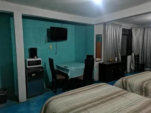 Habitación de hotel con escritorio y habitación con 2 camas en Hospedaje La Cienega en Zacatlán