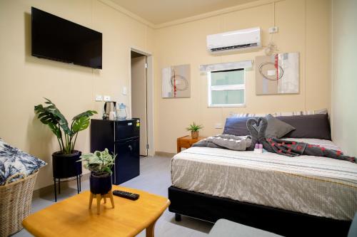 Green Hills Accommodation Village في بورت مورسبي: غرفة نوم مع سرير وتلفزيون على الحائط