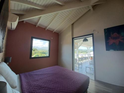 una camera con letto viola e finestra di Les Balcons du Parc a Petit-Bourg