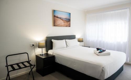 a bedroom with a large white bed and a chair at Petrie Mill Motel in Petrie