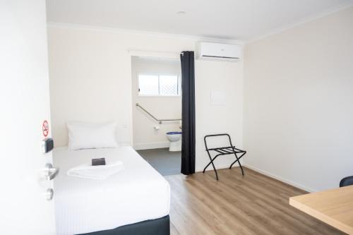 a small room with a bed and a chair at Petrie Mill Motel in Petrie