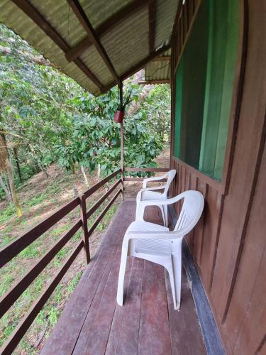 two white chairs sitting on the porch of a house at Pousada Amazônia Encantada in Iranduba