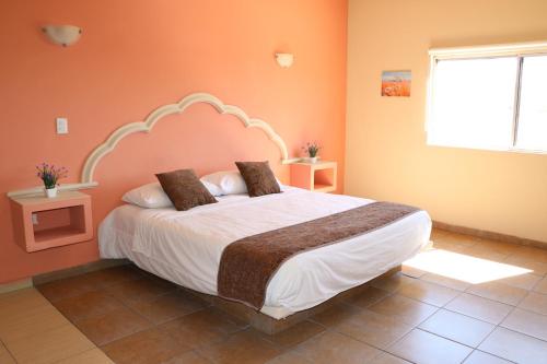 a bedroom with a large bed with orange walls at Hotel Parque Inn in Hermosillo