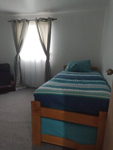 a bedroom with a bed and a window with curtains at Casa de campo Llifén Futrono Lago Ranco in Ranco