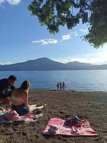 a couple sitting on a beach next to the water at Casa de campo Llifén Futrono Lago Ranco in Ranco