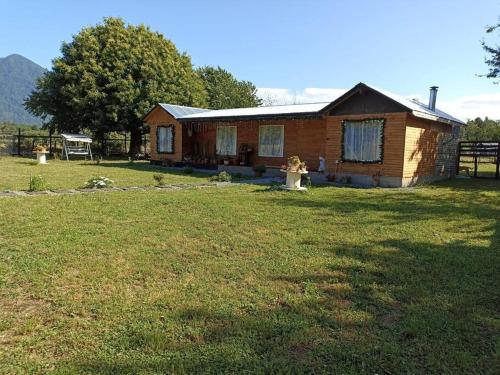 a small wooden house in a field with a yard at Casa de campo Llifén Futrono Lago Ranco in Ranco